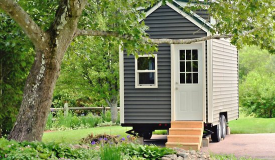 Tiny-House-bauen-14 Tiny House auf Rädern neben einem Baum.